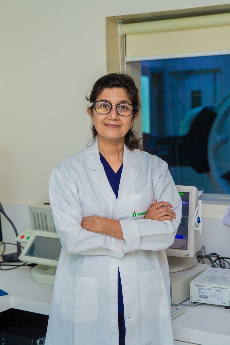 Confident female doctor with arms crossed in a modern medical laboratory setting in Delhi, India.